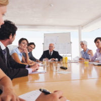 Men and women seated around a conference table using an FM system (Courtesy of Phonak)