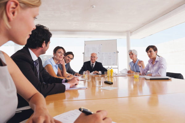 Men and women seated around a conference table using an FM system (Courtesy of Phonak)