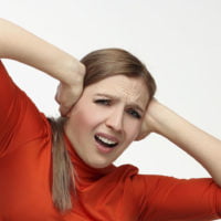 Woman holding her hands to her ears due to tinnitus (Courtesy of Auris Medical)