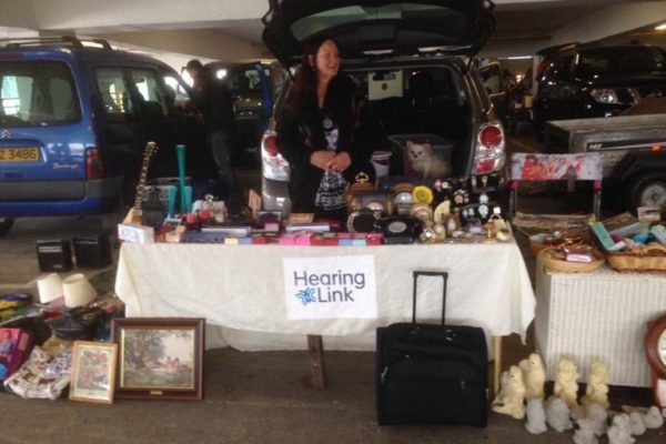 Ramona stands behind a stall at a car boot sale