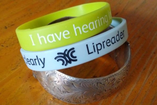 two silicon hearing loss wristbands and a metal bracelet
