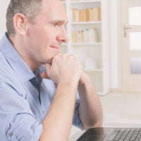 A man with hearing aids looking at a laptop