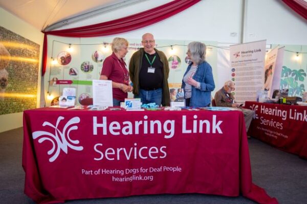 Peer support volunteer speaking to couple at information event and providing hearing information