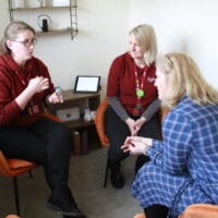 Three women sitting in a comfortable room supporting each other.