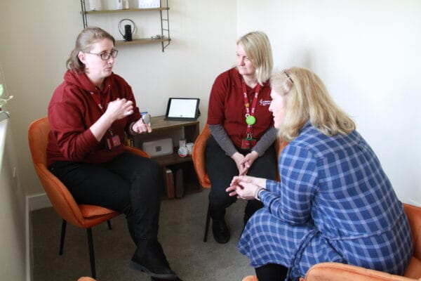 Three women sitting in a comfortable room supporting each other.